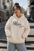 KinnPorsche Hoodie visto de frente, modelo caminando por una calle de día
